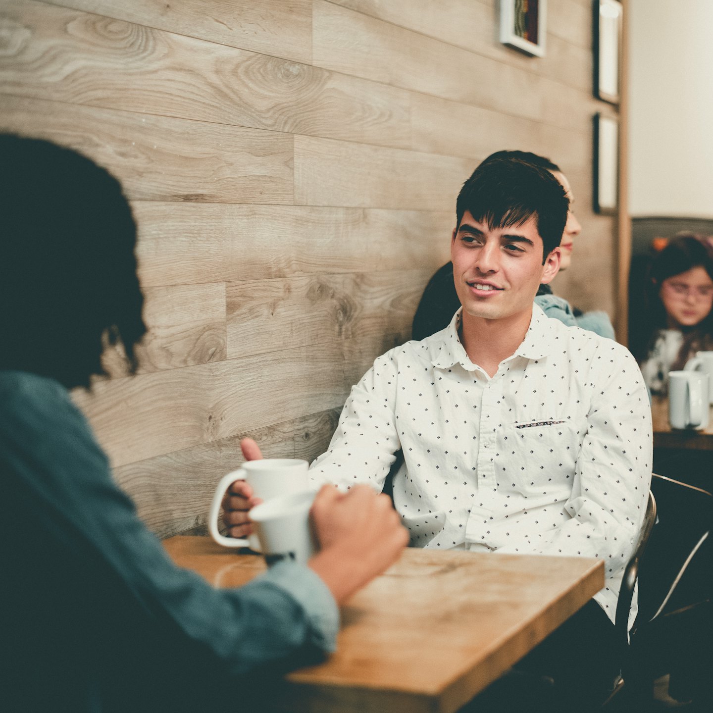 Two people talking over coffee at a cafe table.